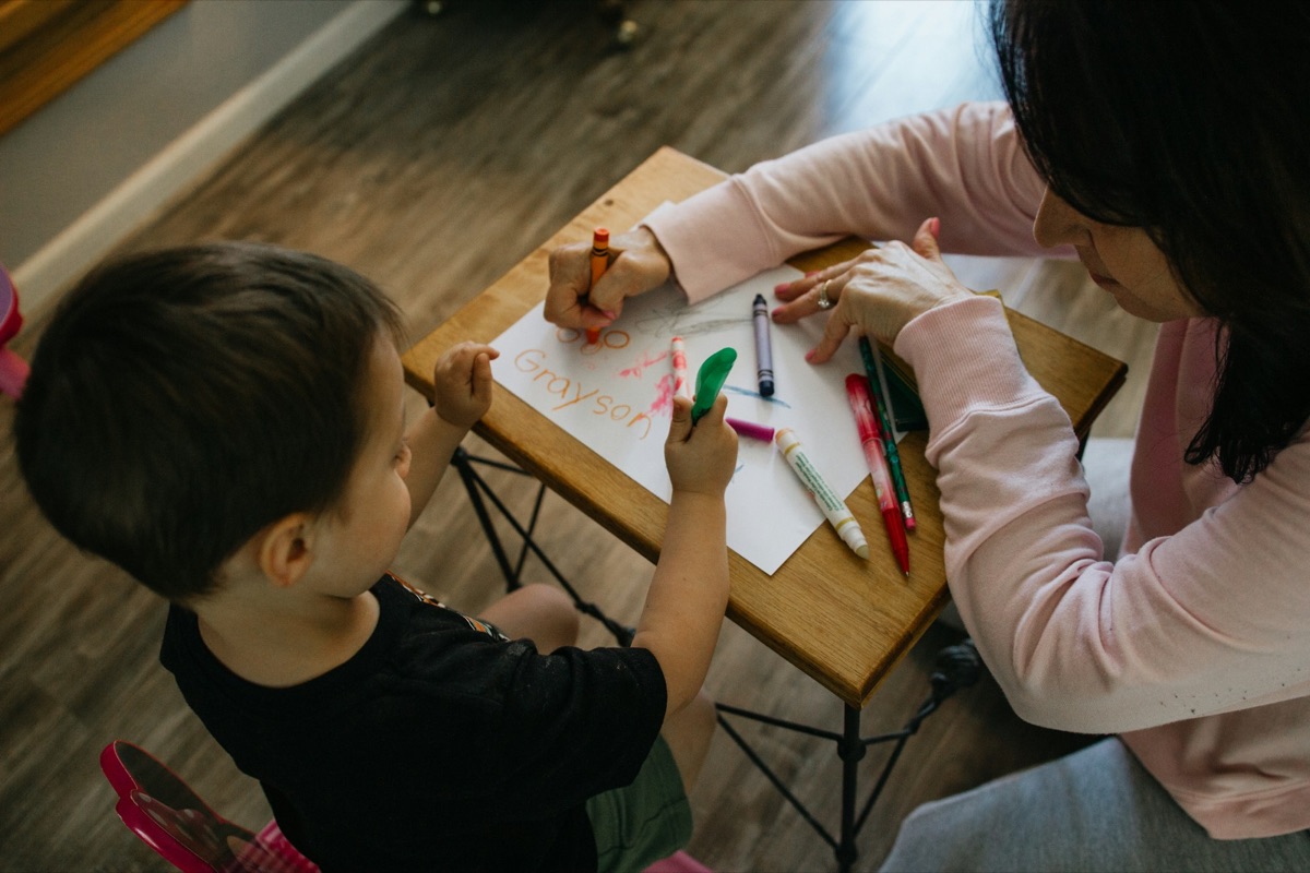 An adult and a child drawing together at a low table
