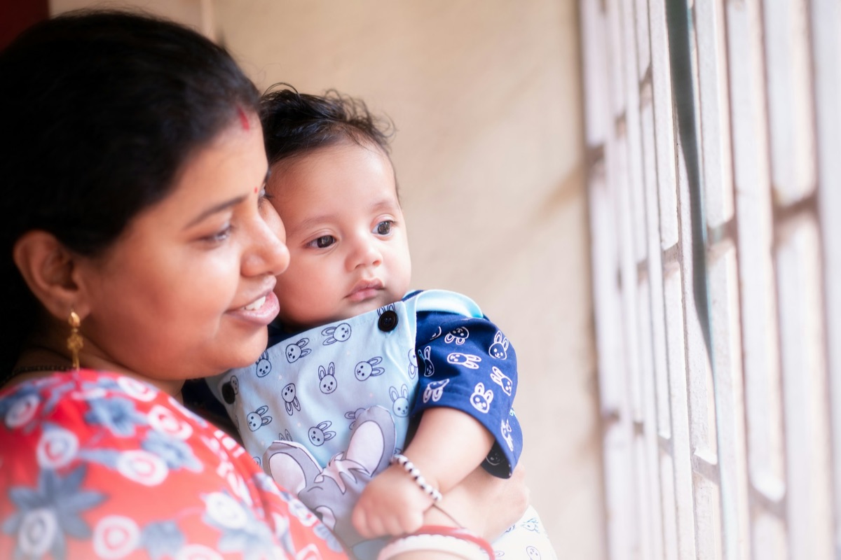 A teacher holding a baby by a window