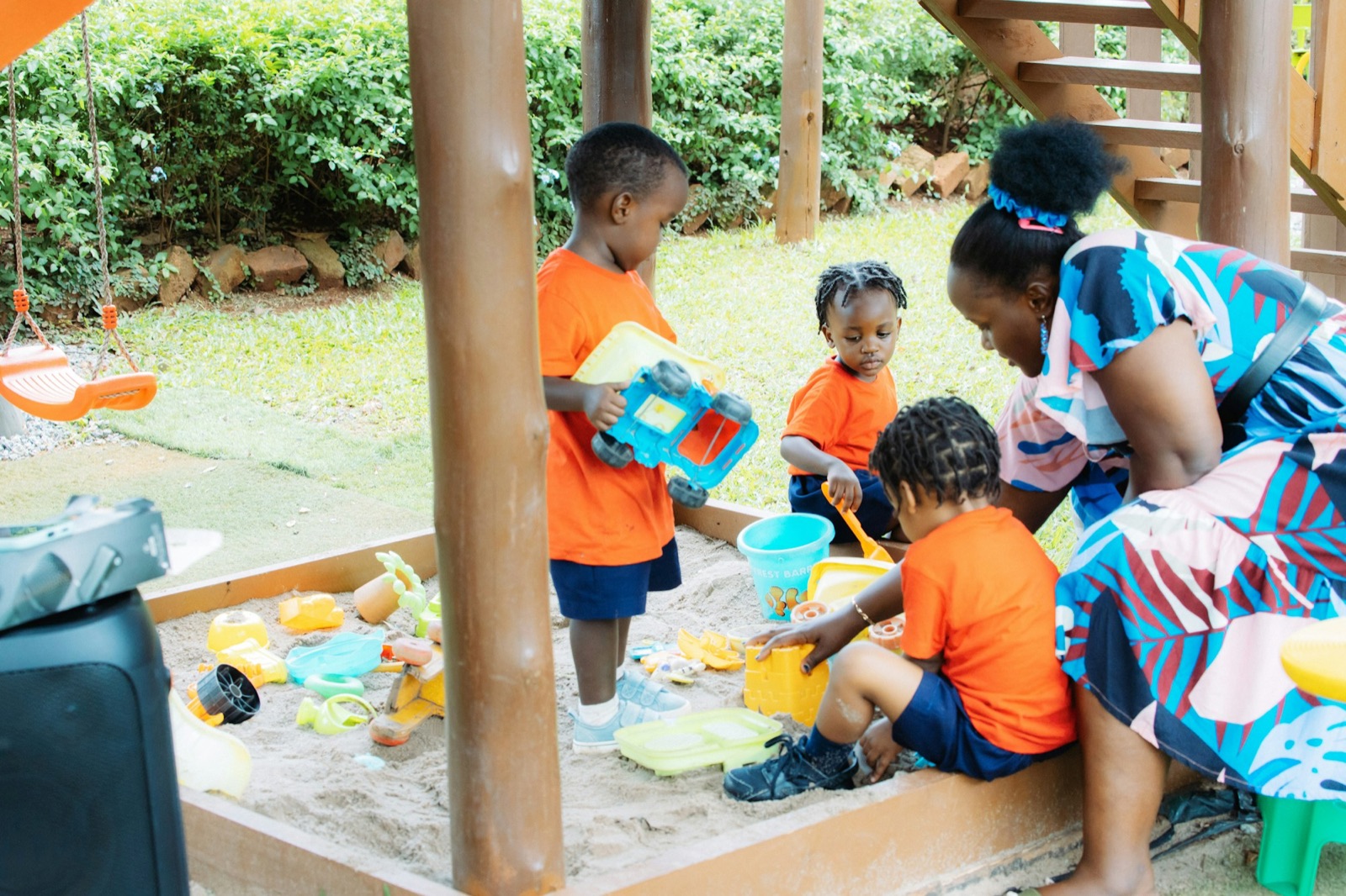 A teacher and children playing in a sandbox