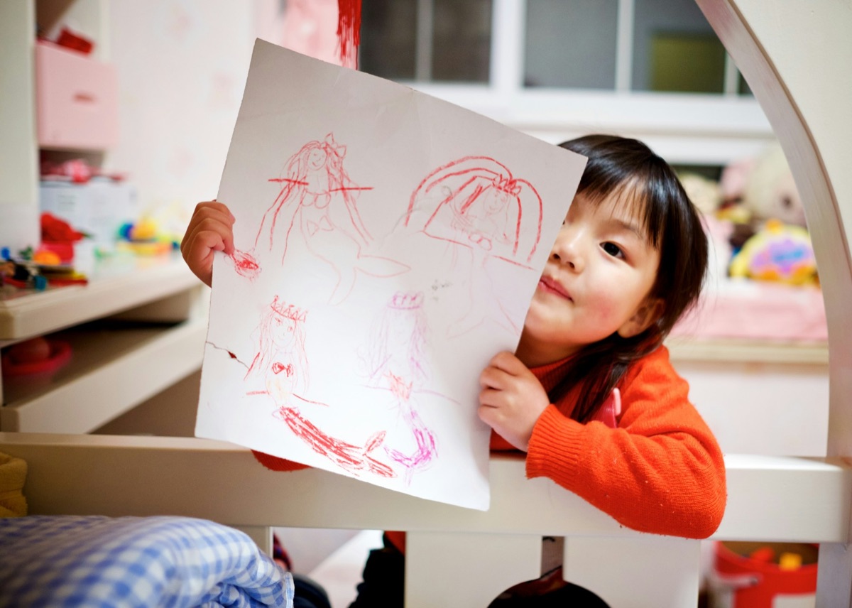 A preschooler holding up her drawing
